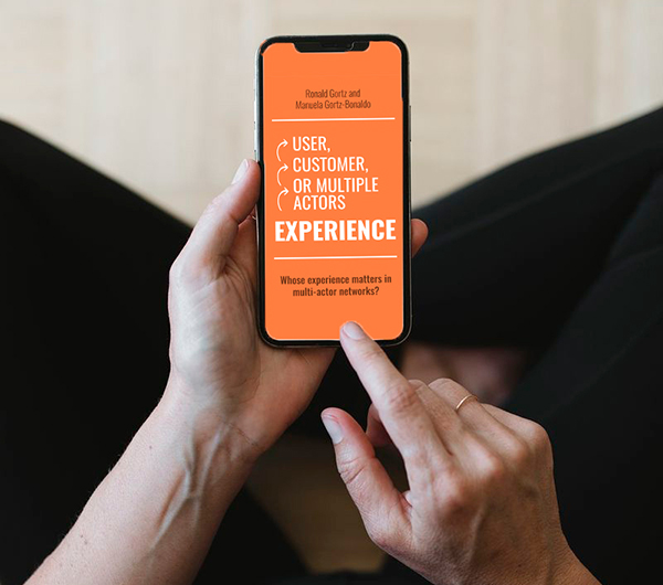 A person holds a smartphone showing the cover of the book User Experience, by author Manuela Gortz Bonaldo